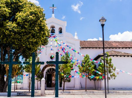Téléchargez les photos : Eglise emblématique de San Lorenzo avec des drapeaux de prière colorés et trois croix chrétiennes dans son parvis, Zinacantan, Chiapas, Mexique - en image libre de droit