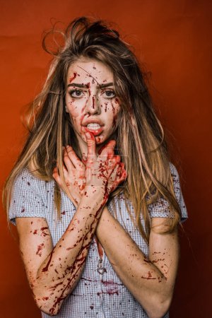 Aggressive girl in blood. Bloody mess. Halloween woman on red background isolated. A terrible Halloween