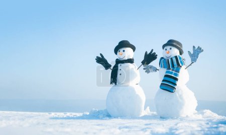 Snowman holding hands outdoors. Winter snowman in black hat, scarf and gloves. Christmas winter banner with snowman. Winter greeting card with with snowman