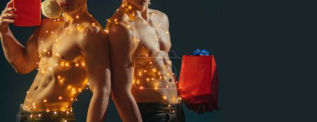 Photo for New year strip and gifts for adults. Call boys or sexy athlete men at x-mas. Sexy muscular men. Concept of the twins. Two twin brothers with bare naked body torso - Royalty Free Image