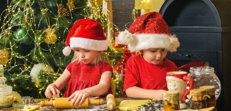 Foto de Las tradiciones navideñas. Niños haciendo galletas de Navidad. Niños felices hornean y decoran galletas - Imagen libre de derechos