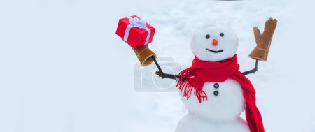 Téléchargez les photos : Bonhomme de neige avec cadeau de Noël. Cadeau bonhomme de neige présente concept. Un cadeau de bonhomme de neige. Conception de bannière affiche vacances - en image libre de droit