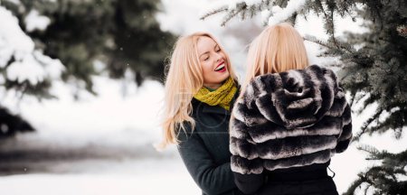 Photo for Winter woman friends talking on winter snowy background outdoor. Portrait of young beautiful women couple having fun. Models walking in winter street. Female winter fashion concept - Royalty Free Image