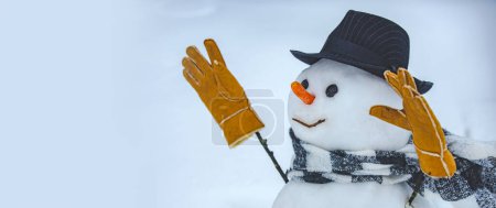 Téléchargez les photos : Bannière d'hiver. Bonhomme de neige en écharpe, chapeau et gants chauds d'hiver. Joyeux Noël et Joyeuses Fêtes. Mignon petit bonhomme de neige en plein air - en image libre de droit