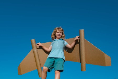 Foto de Niño feliz jugando con jetpack de juguete. Piloto de niños divirtiéndose en el cielo al aire libre. Éxito, innovación infantil y concepto de líder - Imagen libre de derechos