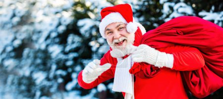Téléchargez les photos : Père Noël avec grand sac. Bonne année. Santa brouillard magique marchant le long du champ. Père Noël avec un énorme sac. Souhaitez-vous joyeux Noël - en image libre de droit