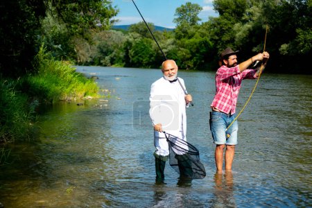 Photo for Father and mature son fisherman fishing with a fishing rod on river - Royalty Free Image