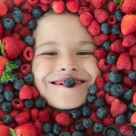 Foto de Cara de niño bayas de cerca. Vista superior de la foto de la cara de niño con berri. Berry está cerca de la cara de los niños. Lindo niño come bayas. Niño comiendo vitaminas. Cerca de cara de los niños - Imagen libre de derechos