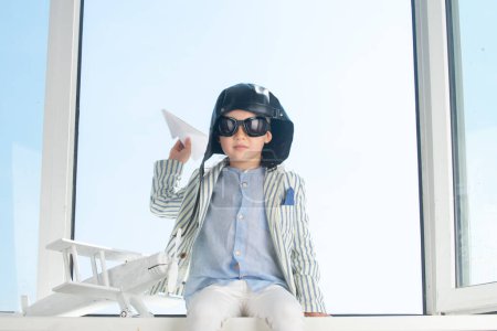 Photo for Dreams of flight. Child with pilot goggles and helmet against the sky. Dreams of travels. Little dreaming child with a toy airplane plays outdoors - Royalty Free Image