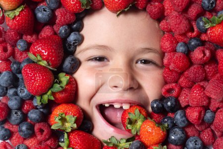 Téléchargez les photos : Vitamines de berrie. Mélange de baies. Les enfants font face avec des fruits de baies fraîches. Mélange assorti de baies fraise, myrtille, framboise, mûre sur fond. Baies nutritionnelles saines pour les enfants - en image libre de droit