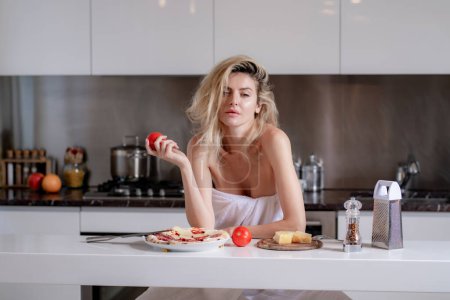 Photo for Woman with ingredients for pizza, cheese, sausage and tomato. Sexy housewife have breakfast at kitchen. Domestic lifestyle. Sensual woman eating breakfast in the kitchen in the morning - Royalty Free Image