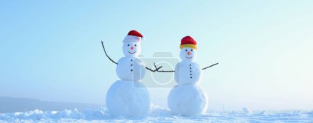 Photo for Couple of two snowman holding hands outdoors. Snowman on the snow outdoor background. Christmas banner with snowman. New year greeting card with with snowman - Royalty Free Image