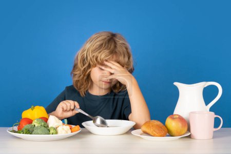 Photo for Bad appetite. Sad kid eating healthy food on studio iosolated background. Baby eat soup with spoon. Kid eating soup - Royalty Free Image