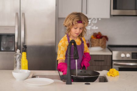Photo for Clean washed dishes, dishwashing liquid with foam. Kid washing the dishes in the kitchen sink. Detergents and cleaning accessories. Cleaning service. Little boy housekeeping - Royalty Free Image