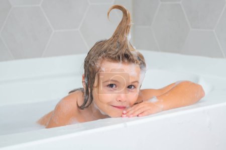 Foto de Niño con espuma de champú y burbujas en el baño de pelo. Cara divertida de niño en espuma, cuidado del cabello y concepto de higiene. Bañera con burbuja de jabón - Imagen libre de derechos