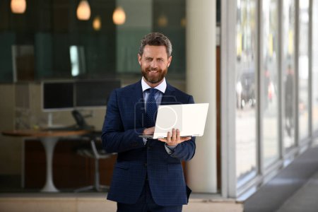 Photo for Businessman with notebook outdoor. Confident business expert. Handsome man in suit holding laptop against office background - Royalty Free Image