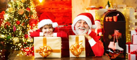 Photo for Santa grandfather with kid child hold gift presents. Santa child grandfather and grandson. Child play with real grandfather Santa near christmas tree - Royalty Free Image