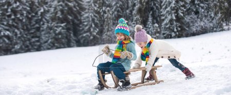 Niños divertidos en paseo de nieve en trineo. Juegos de invierno al aire libre. Feliz Navidad concepto de vacaciones familiares. Los niños disfrutan de las vacaciones