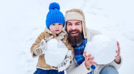 Téléchargez les photos : Père et fils excités faisant boule de neige dans la neige. Papa et enfant jouant avec boule de neige en hiver en plein air - en image libre de droit