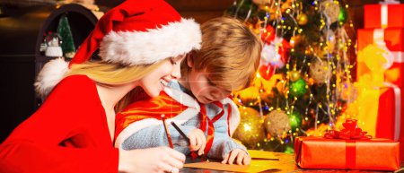 Foto de Feliz Navidad y Feliz Año Nuevo. Madre e hijo escribiendo una carta a Santa. Niño escribir wishlist a santa - Imagen libre de derechos