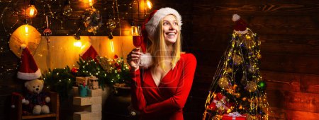 Foto de Santa mujer sosteniendo la copa de champán celebra la Navidad en la habitación decorada en casa - Imagen libre de derechos