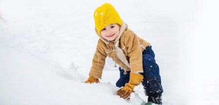 Téléchargez les photos : Joyeux garçon enfant jouant avec la neige lors d'une promenade hivernale dans la nature. Enfant heureux s'amuser sur le terrain d'hiver avec de la neige. Émotion de Noël d'hiver - en image libre de droit