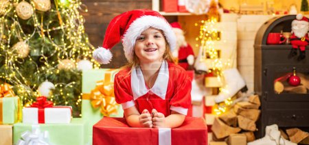 Téléchargez les photos : Des petits enfants mignons qui fêtent Noël. Les enfants de Noël célèbrent les vacances. Joyeux enfant mignon dans le chapeau de Père Noël avec cadeau ont un Noël - en image libre de droit