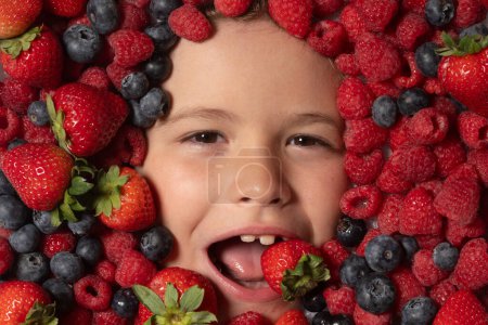 Téléchargez les photos : Une alimentation saine pour les enfants. Mélange de fraise, myrtille, framboise, fond de mûre. Les baies se rapprochent du visage des enfants. Des baies fraîches, vue de dessus. Mélange de fruits crus de baies fraîches - en image libre de droit
