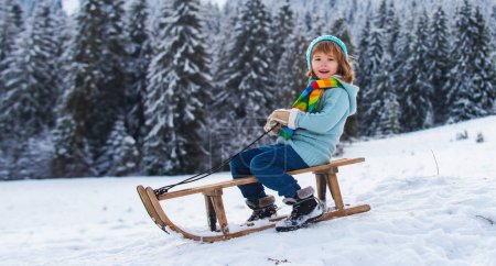 Photo for Child boy sledding on winter snowy winter park - Royalty Free Image