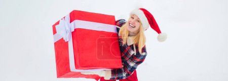 Téléchargez les photos : Service de livraison d'hiver. Femme portant un grand cadeau isolé sur fond d'hiver de neige. Portrait de Santa femme avec un énorme cadeau rouge - en image libre de droit