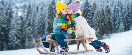 Photo for Happiness and kids love. Little couple on a sleigh kissing. Child friends kissed - Royalty Free Image