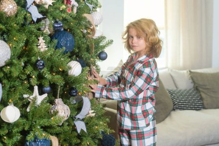 Photo for Merry Christmas. Christmas and happy holidays at home. Cheerful cute kid boy decorated christmas tree. Kids with Christmas ball and toys near tree in room - Royalty Free Image