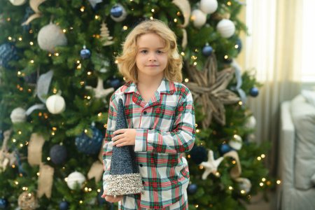 Photo for Little kid celebrating Christmas or New Year near Christmas tree at home - Royalty Free Image