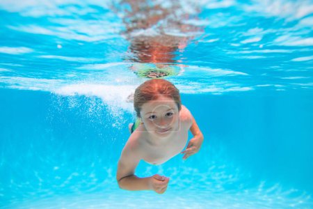 Foto de Niños bajo el agua nadando en la piscina, niños sanos nadando y divirtiéndose bajo el agua. Concepto vacaciones de verano - Imagen libre de derechos