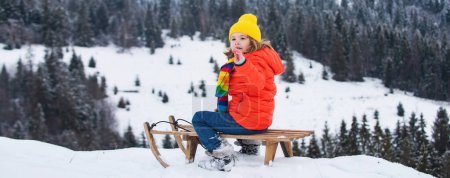 Téléchargez les photos : Enfant garçon luge en hiver. Enfant chevauchant sur des glissades de neige en hiver, bannière - en image libre de droit