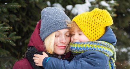 Téléchargez les photos : Jeune maman étreint son joli gosse en hiver en plein air. Mère marche avec son petit fils en hiver - en image libre de droit