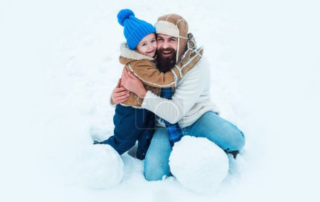 Photo for Daddy and boy smiling and hugging. Father and son making snowball in the snow. Dad and child playing with snowball on winter outdoor. Winter portrait of dad and child in snow outdoor - Royalty Free Image