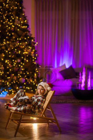 Foto de Feliz Navidad y Feliz Año Nuevo. Acogedora casa cálida de invierno por la noche. Niño celebrando la Nochebuena - Imagen libre de derechos