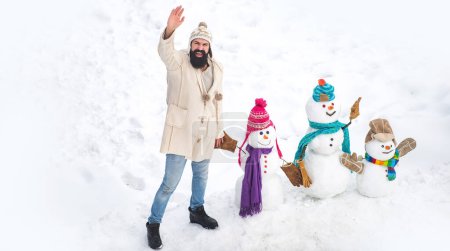 Foto de Muñeco de nieve en el soleado día de invierno con padre feliz. Padre haciendo familia de muñeco de nieve para niño. Papá desea feliz Navidad y Feliz Año Nuevo. Tarjeta de felicitación de arte festivo - Imagen libre de derechos