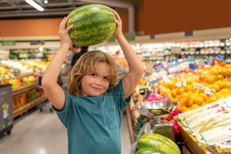 Foto de Niño con sandía. Divertido niño lindo en las compras en el supermercado. Una tienda de comestibles. Compra de comestibles, concepto de estilo de vida saludable - Imagen libre de derechos