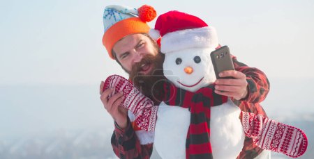 Téléchargez les photos : Drôle de bonhomme de neige. Homme avec bonhomme de neige sur fond d'hiver extérieur. Bonhomme de neige pour bannière d'hiver - en image libre de droit