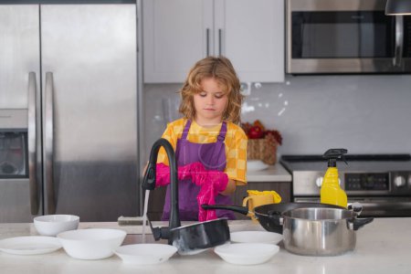 Photo for Cleaning house. Child doing and wiping dishes in kitchen. Little kid cleaning at home. Child doing housework having fun. Cute child boy helping with housekeeping in kitchen, cleaning - Royalty Free Image