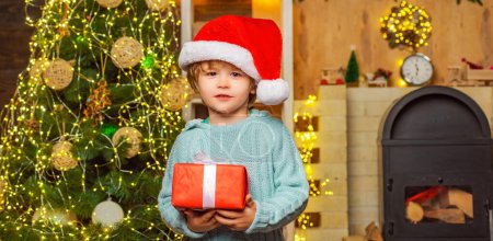 Téléchargez les photos : Garçon enfant avec coffret cadeau ou cadeau à l'intérieur. Nouvelle année concept. Des émotions cadeaux. Émotion de Noël d'hiver. Enfant de Noël tenant une boîte cadeau rouge - en image libre de droit