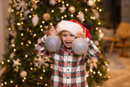 Foto de Un niño excitado en casa en Navidad. Niño pequeño celebrando Navidad o Año Nuevo - Imagen libre de derechos