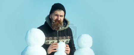 Foto de Feliz Navidad y feliz año nuevo. Hombre haciendo muñeco de nieve al aire libre. Hombre con muñeco de nieve sobre fondo de invierno. Hombre de nieve para bandera de invierno - Imagen libre de derechos