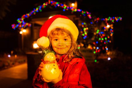 Téléchargez les photos : Bonne année et joyeux Noël. Vacances d'hiver et fête pour les enfants. Enfant à la maison de Noël extérieur - en image libre de droit