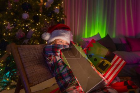 Photo for Lighting in magic Christmas night at cozy home. Cute child on Christmas night at home. Merry Christmas - Royalty Free Image