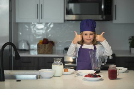 Téléchargez les photos : Chef cuisinier enfant apprend à faire un gâteau dans la cuisine de la maison - en image libre de droit
