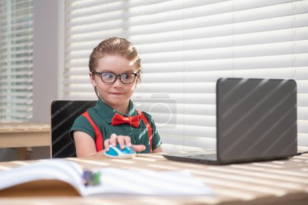 Foto de Un chico listo en casa escribiendo deberes. Estudiante con computadora portátil lista para estudiar. Escuela remota, aprendizaje en línea. Aprendizaje de niños en casa - Imagen libre de derechos