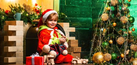 Foto de Niño en sombrero de Santa Claus y disfraz divirtiéndose jugando con juguetes - Imagen libre de derechos